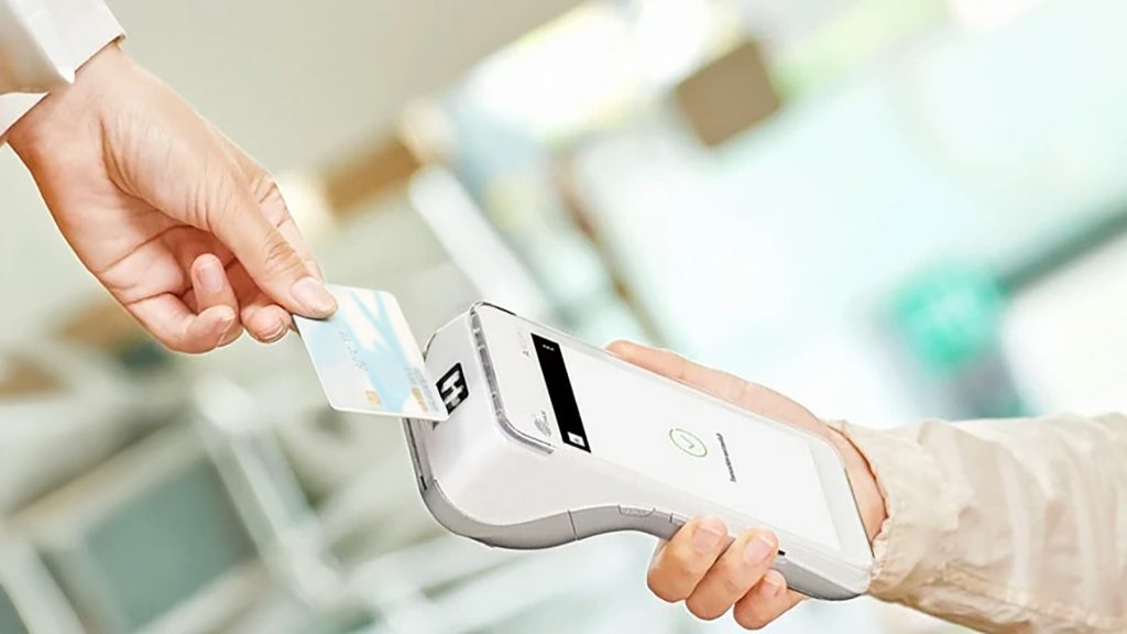 Irish payment processors comparison showing customer using contactless payment at local business