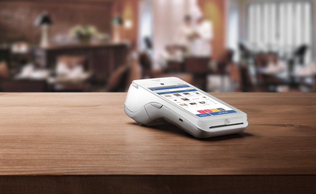 PAX A920PRO card machine displaying payment analytics dashboard comparison data on counter