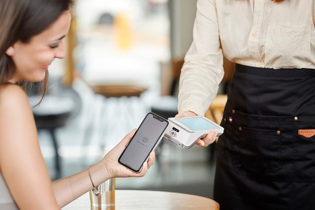 Waiter using no contract card machine for contactless payment in Irish restaurant - flexible payment terminal solution