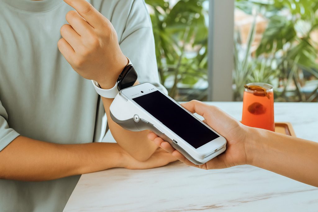 Person making contactless payment with smartwatch on PAX A920 PRO showing settlement times comparison Ireland funding speed options