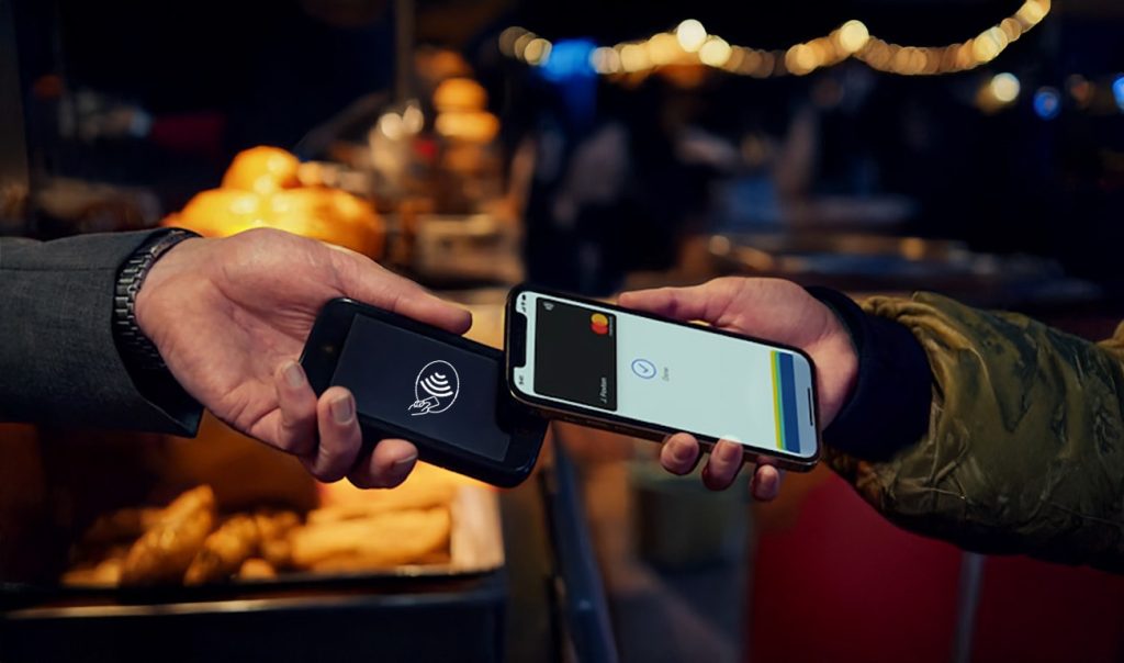 Hand holding Castles S1 Mini 2 card machine with customer paying by mobile phone at food truck showing market stall payments Ireland solutions