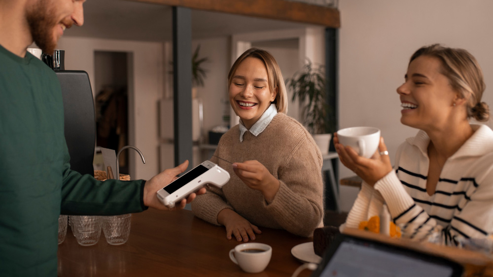 Waiter holding PAX A920 PRO mobile payment terminal Ireland processing contactless payment from customer in Irish restaurant