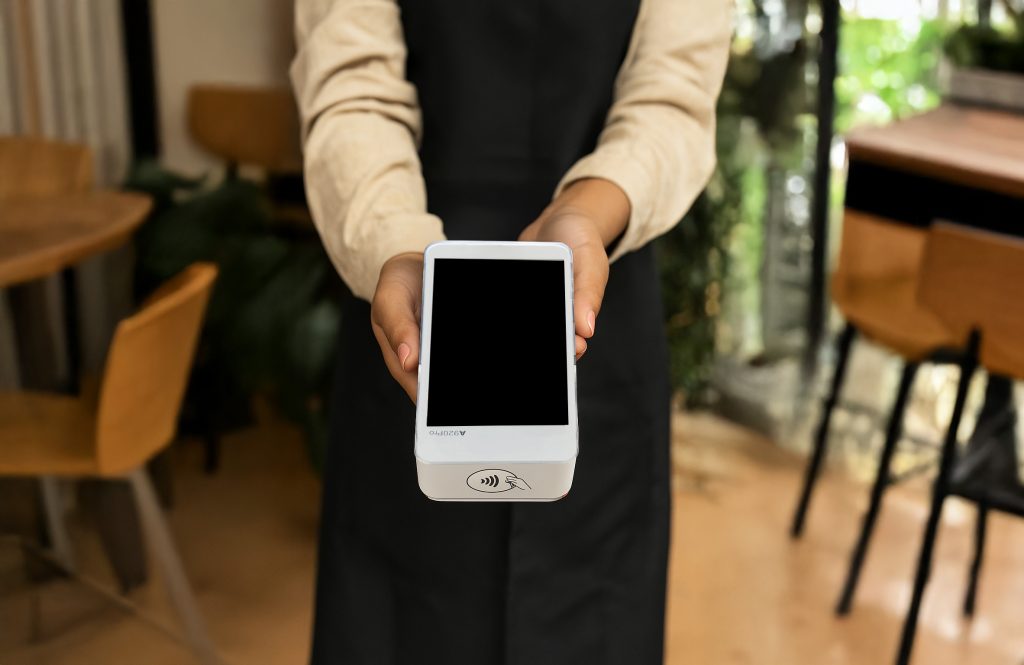 Barista holding PAX A920 PRO card machine for small business payments Ireland in coffee shop startup