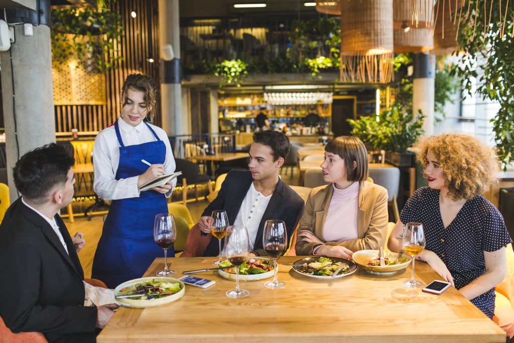 Waiter taking order from group of friends at Irish restaurant considering wireless card machine Ireland for tableside payments
