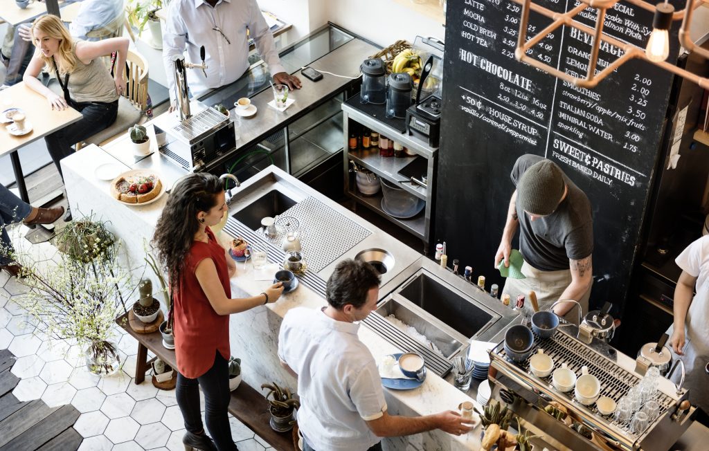 Busy coffee shop counter top view showing queue where contactless payment Ireland reduces transaction times compared to chip and PIN