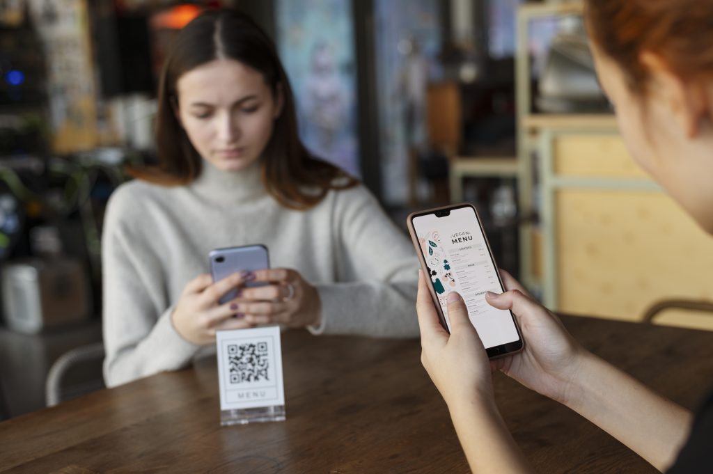 Two women using smartphone to scan QR code demonstrating QR payments Ireland contactless scan to pay transaction process