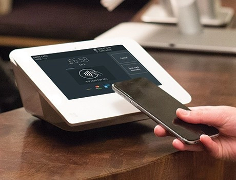 Business owner processing a contactless payment on a Clover Mini card machine in Ireland
