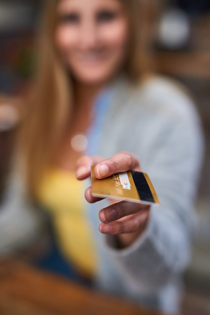 Customer handing over a debit card to pay with low card transaction fees Ireland retail shop