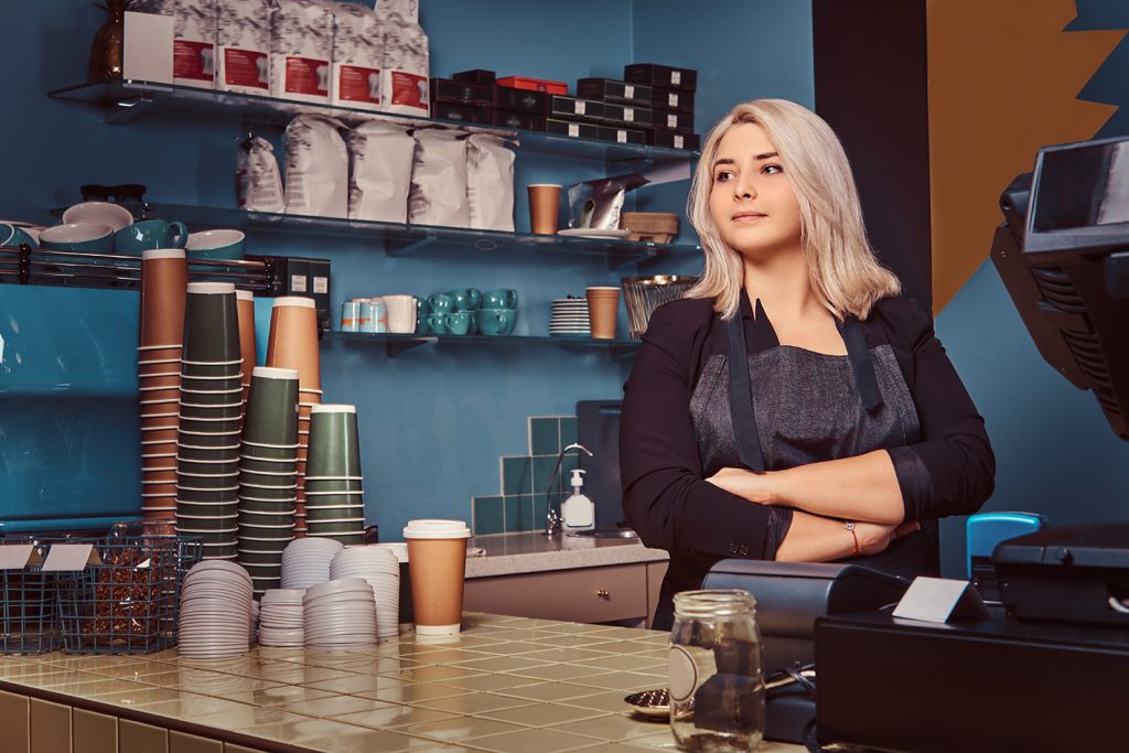 Experienced female barista at coffee shop managing restaurant payment processing Ireland merchant costs